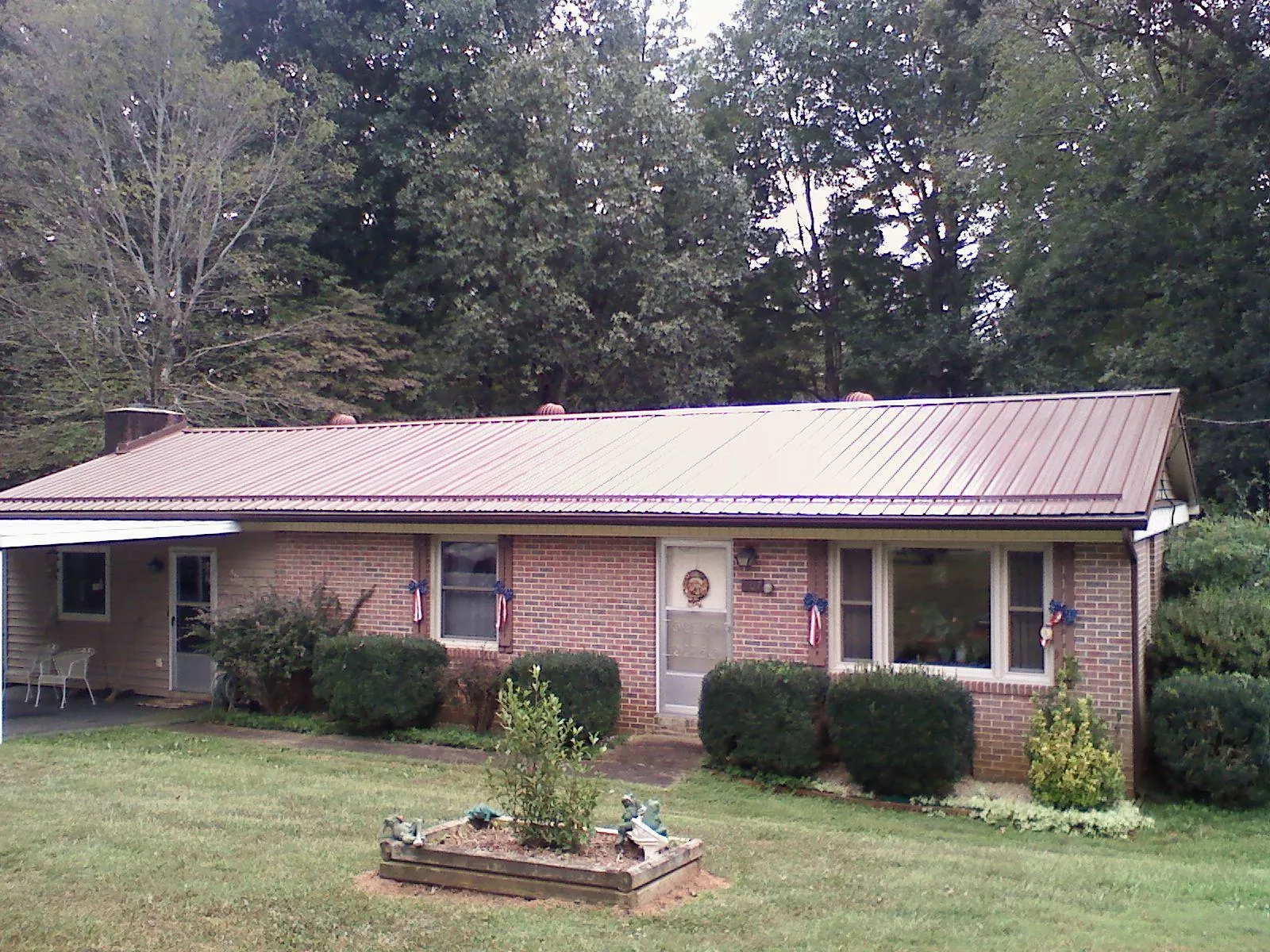 Bronze metal roof on a brick ranch home with a carport in Frederica