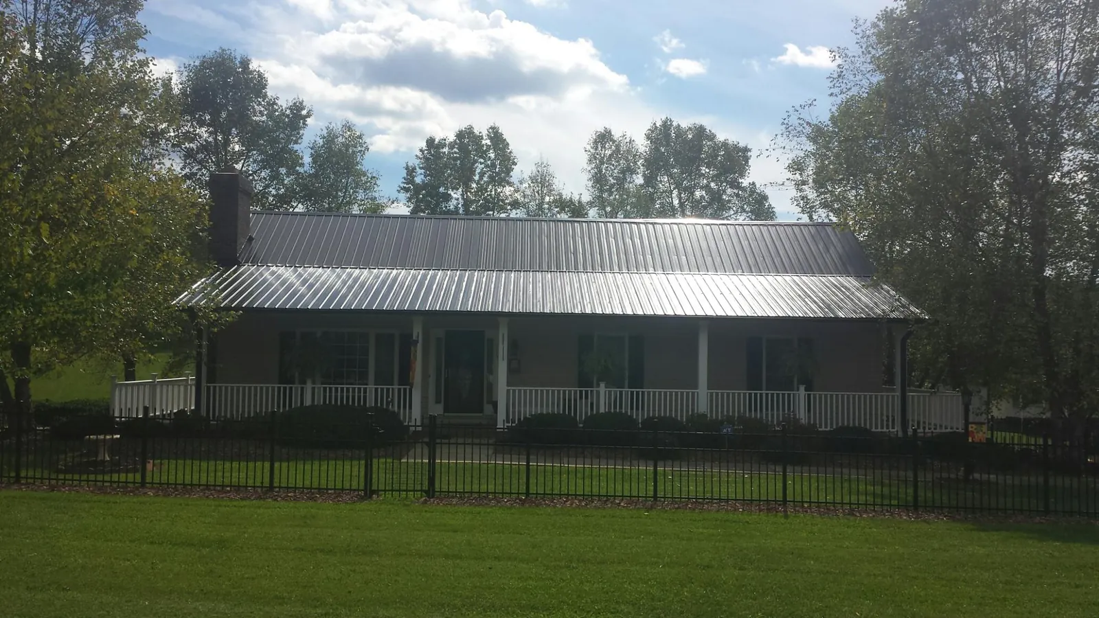 Gray metal roof on a brick ranch with a full width front porch — Gutter Guard Installation work by our crew in Frederica