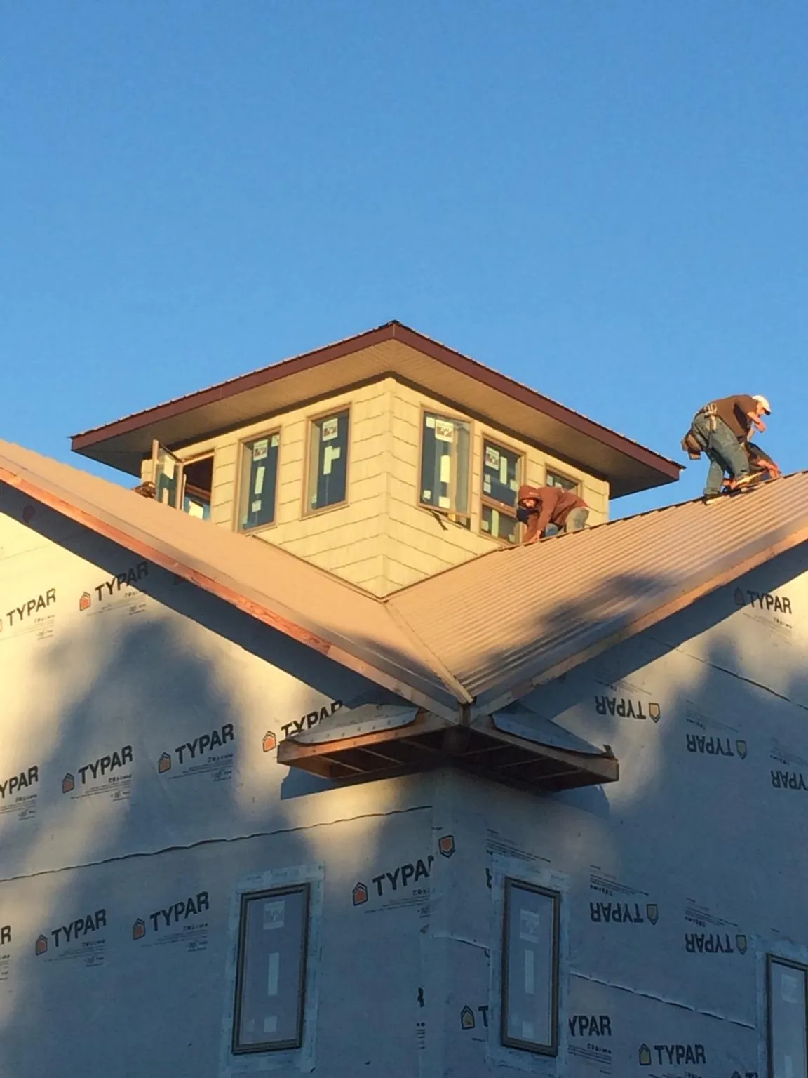 Roofers working around a rooftop cupola on a new metal roof at sunset — Roof Waterproofing in Frederica by Roofing Brothers